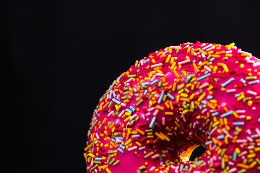 Pink glazed donut with sprinkles isolated. Close up of colorful donut.