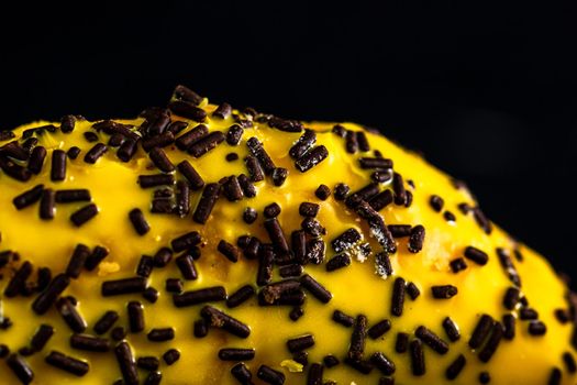 Yellow glazed donut with sprinkles isolated. Close up of colorful donut.