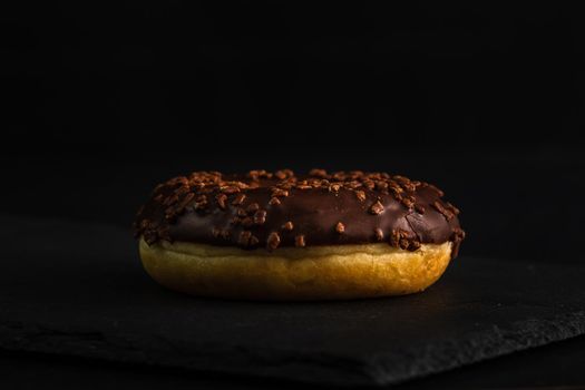 Chocolate glazed donut with chocolate chips isolated. Close up of delicious donut.