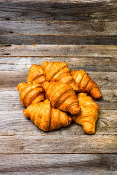 Delicious, fresh croissants isolated on wooden board. French breakfast concept.