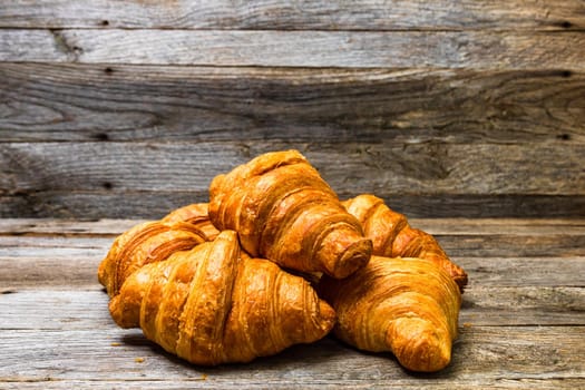 Delicious, fresh croissants isolated on wooden board. French breakfast concept.