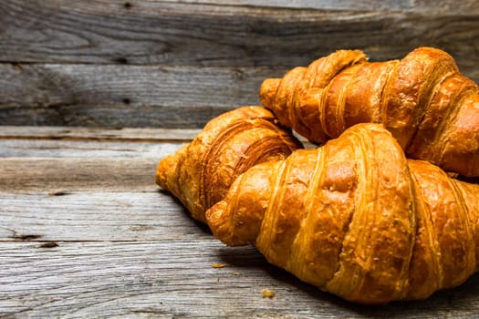 Delicious, fresh croissants isolated on wooden board. French breakfast concept.