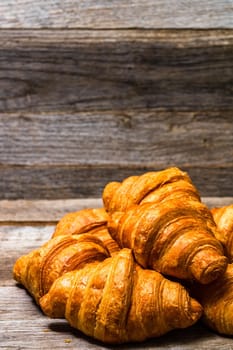 Delicious, fresh croissants isolated on wooden board. French breakfast concept.