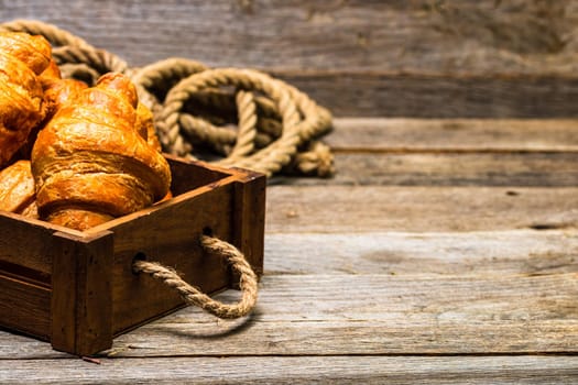 Wooden crate with delicious, fresh croissants isolated. French breakfast concept.