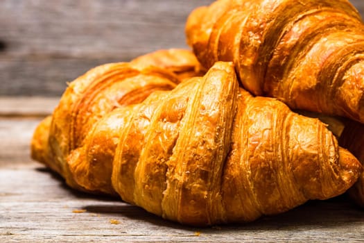 Delicious, fresh croissants isolated on wooden board. French breakfast concept.