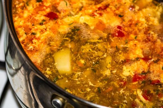 Preparation of soup with chicken and vegetables. Close up of boiling soup.