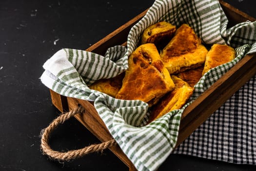 Freshly baked homemade ham and cheese puff pastry in a rustic crate.