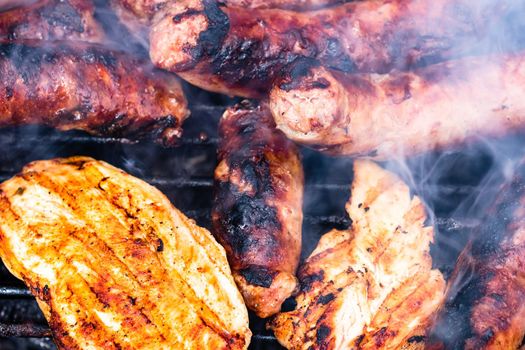 Close up on details of homemade chicken, pork steak and sausages on barbecue grill. Barbecue, grill and food concept.