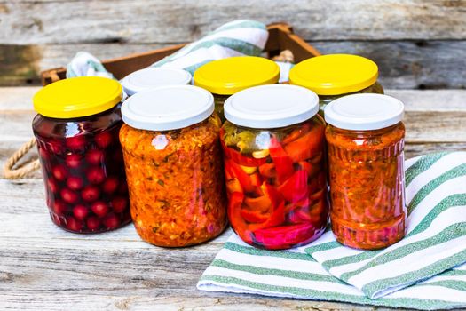 Jars with variety of canned vegetables and fruits, jars with zacusca. Preserved food concept in a rustic composition.