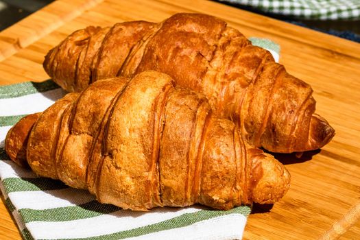 Detail of fresh croissant on wooden table. Food and breakfast concept. Close up photo of French buttery croissant