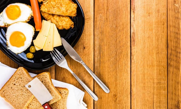 Fried egg, wholegrain toast, cheese, hotdog and cup of coffee for breakfast over wooden table, top view, copy space, breakfast concept