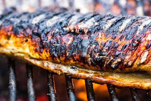 Grilled fish with smoke on a charcoal barbecue. Close up fish on the grill