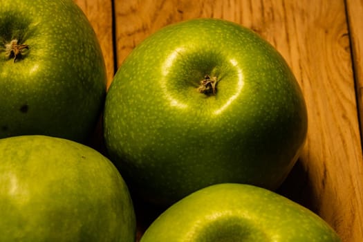 Close up photo of green apples on a wooden board.