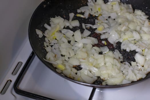 Close up of onion frying in a pan isolated.