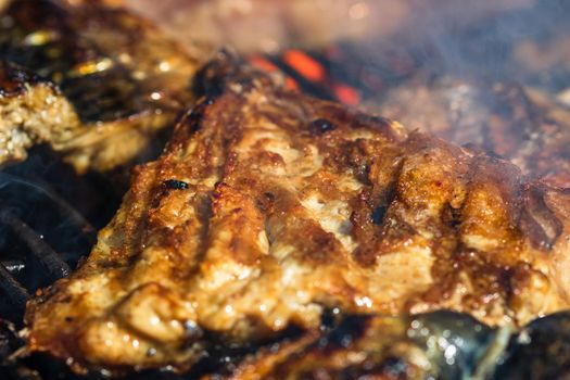 Grilled mackerel fish with smoke on a charcoal barbecue grill.