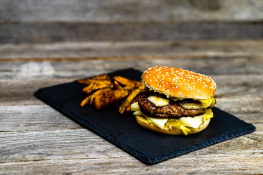 Homemade fresh tasty cheese burger and fried potatoes on a wooden table