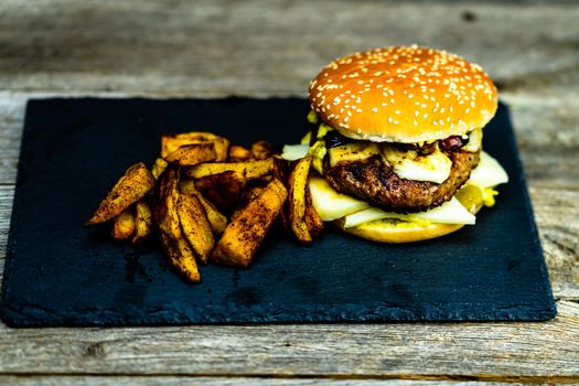 Homemade fresh tasty cheese burger and fried potatoes on a wooden table