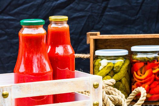 Bottles of tomato sauce, preserved canned pickled food concept isolated in a rustic composition.