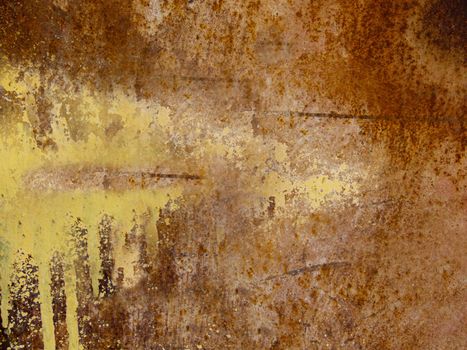 A scratched rusty iron plate with a smudge of yellow paint.Texture or background