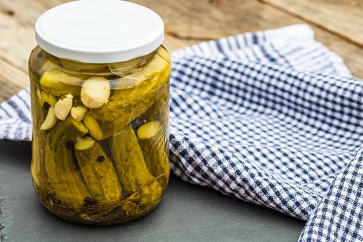 Close up of glass jar with pickles isolated. Preserved food concept, canned vegetables isolated in a rustic composition.