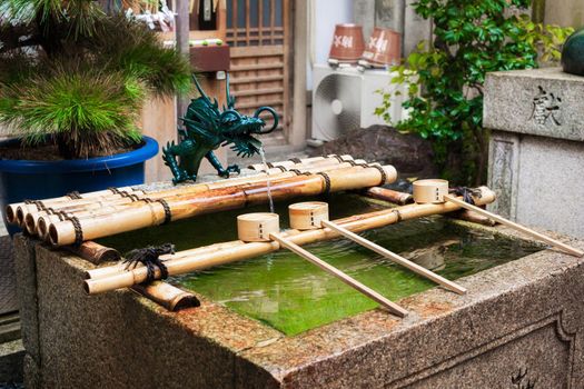 Water ablutions pavilion for a ceremonial purification at the Nishiki Tenmangu Shrine, Kyoto, Japan. Spring natural water flows up from underground.