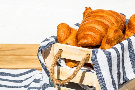 Fresh croissant, puff pastry and buttered french croissant on wooden crate. Food and breakfast concept. Detail of desserts and fresh pastries