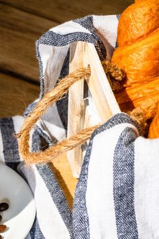 Puff pastry, coffee cup and buttered French croissant on wooden crate. Food and breakfast concept. Detail of coffee desserts and fresh pastries