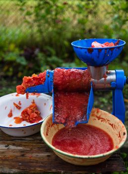 Close up photo of a manual tomato-grinder. Fresh tomatoes, for preparing handmade tomato paste.