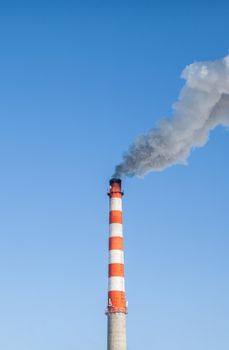 White thick smoke from the boiler room chimney. Smoke against the blue sky. Air pollution. Heating of the city. Industrial zone.