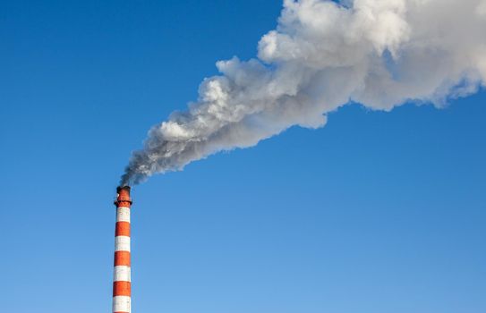 White thick smoke from the boiler room chimney. Smoke against the blue sky. Air pollution. Heating of the city. Industrial zone.