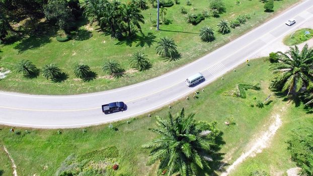 Aerial view from drone of cars are going through a curve road on the mountain with green forest. The transportation road across mountain.