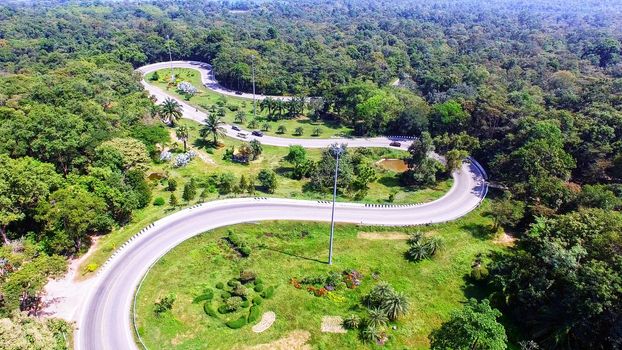 Aerial view from drone of cars are going through a curve road on the mountain with green forest. The transportation road across mountain.