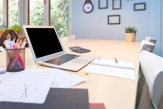 Smart computer and document put on wooden table in Co Working Space, new working office style for startup business owner and freelance.