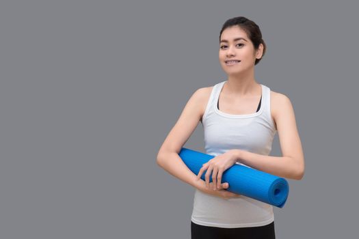 Young asian woman holding her yoga mat at healthy sport gym. Yoga and meditation have good benefits for health. Photo concept for Yoga Sport and Healthy lifestyle