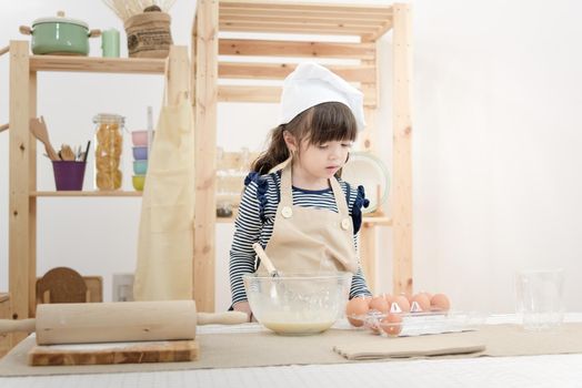 Asian children waiting her mother for preparing the dough to make a cake in the kitchen room on vacation.Photo series of Happy family concept.