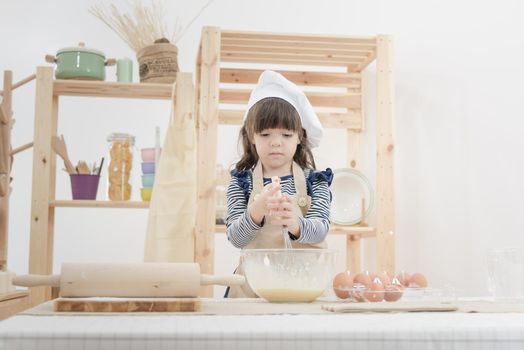 Cute kid enjoy preparing the dough to make a cake in the kitchen room.Photo series of Happy family concept.
