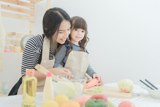 Happy loving family asian mother and her daughter prepare healthy food salad in kitchen room.Photo design for family, kids and happy people concept.