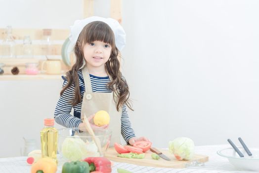 Cute girl prepare healthy food salad in kitchen room.Photo design for family, kids and happy people concept.