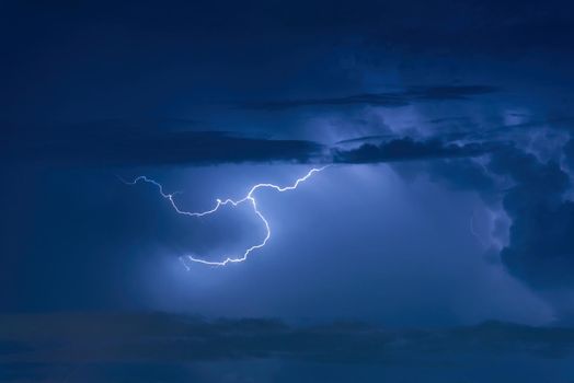 Thunder storm lightning strike on the dark cloudy sky background at night.