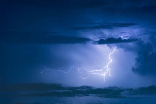 Thunder storm lightning strike on the dark cloudy sky background at night.