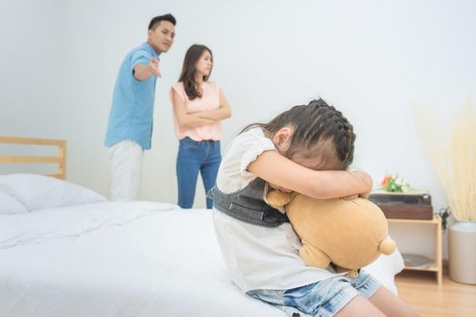 Asian little girl sadness while parent quarrelling in bedroom.Photo design for family problems and unhappy concept.