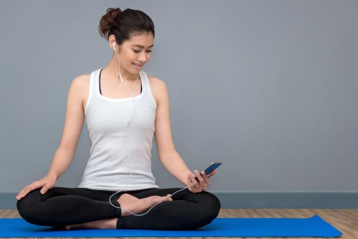 Young asian woman enjoy the music before practicing yoga at yoga healthy sport gym, yoga and meditation have good benefits for health. Photo concept for Yoga Sport and Healthy lifestyle