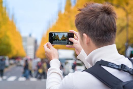 AsianTourists take a photo at Meiji Jingu Gaien in Tokyo, Japan.Meiji Jingu Gaien that has beautiful Ginkgo along the lenght of the street famous for autumn spot in Tokyo,Japan