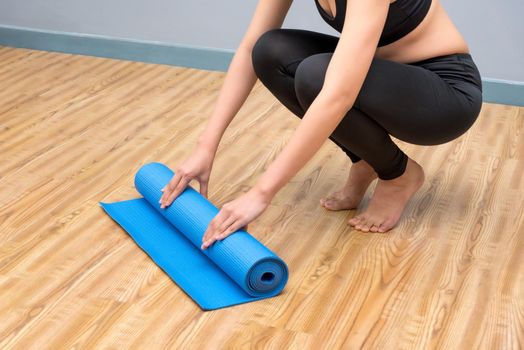 Young asian woman prepare her yoga mat at indoor yoga healthy sport gym. Yoga and meditation have good benefits for health. Photo concept for Yoga Sport and Healthy lifestyle.