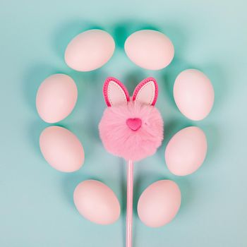 Easter. White eggs with an artificial rabbit on a uniform blue background. Place for text.