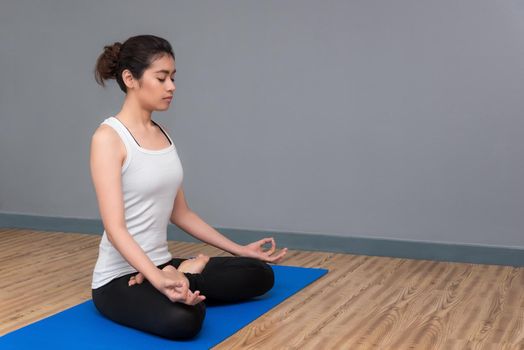 Young woman keep calm and meditates while practicing yoga to at yoga sport gym. Yoga and meditation have good benefits for health. Photo concept with copy space for Yoga Sport and Healthy lifestyle.