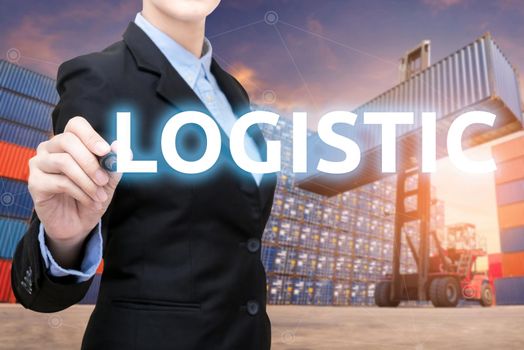Smart business woman is writing Logistic word with forklift lifting cargo container and cargo containers stack in background for global transportation import,export and logistic business concept