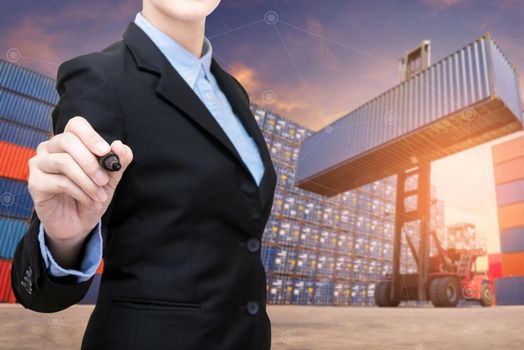 Smart Business woman holds a marker writing with copy space and Forklift truck lifting cargo container in shipping yard in background for transportation import,export and logistic industrial concept