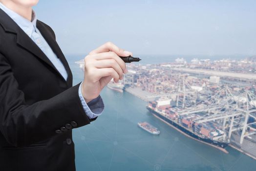 Smart Business woman holds a marker writing and copy space for your text with shipping boat at shipping yard in background for transportation import,export and logistic industrial concept