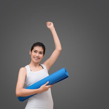 Young asian woman with happy smile holding her yoga mat at yoga healthy sport gym. Yoga and meditation have good benefits for health. Photo concept for Yoga Sport and Healthy lifestyle.